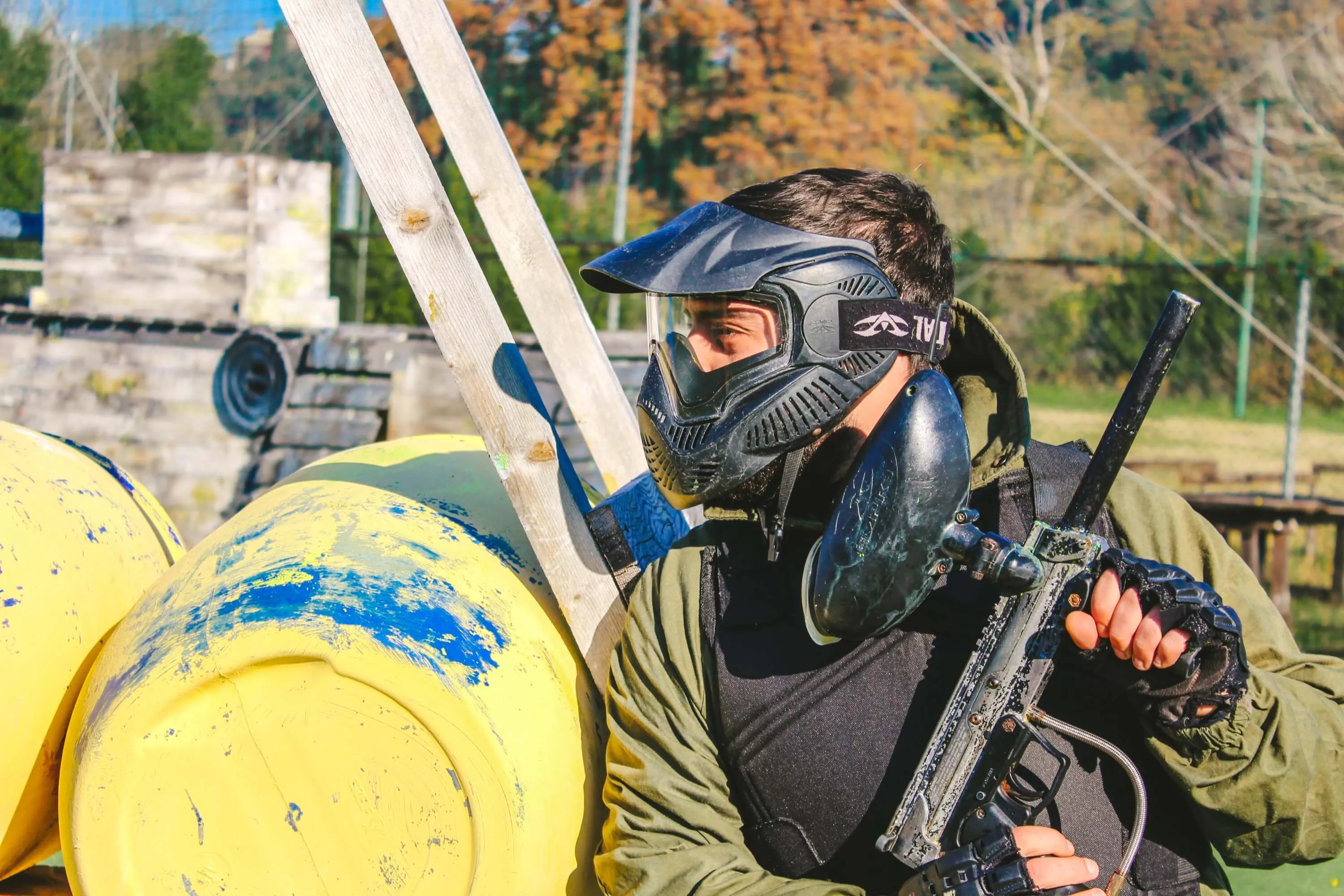 Giocatore con maschera e marcatore al riparo dietro le barricate del campo